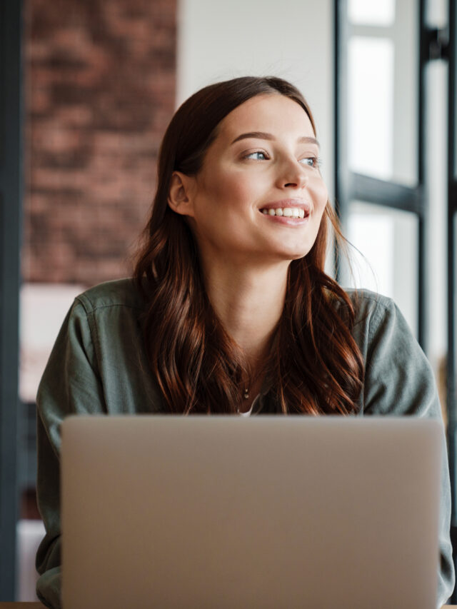 Beautiful smiling woman working with laptop while sitting at table