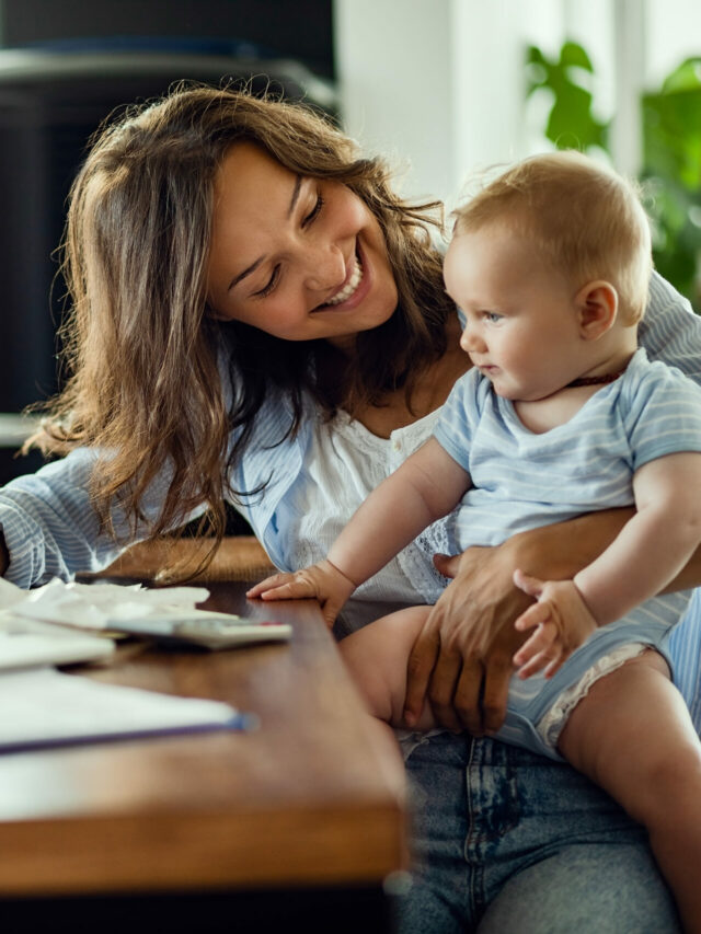 Happy mother talking to her baby while working at home.