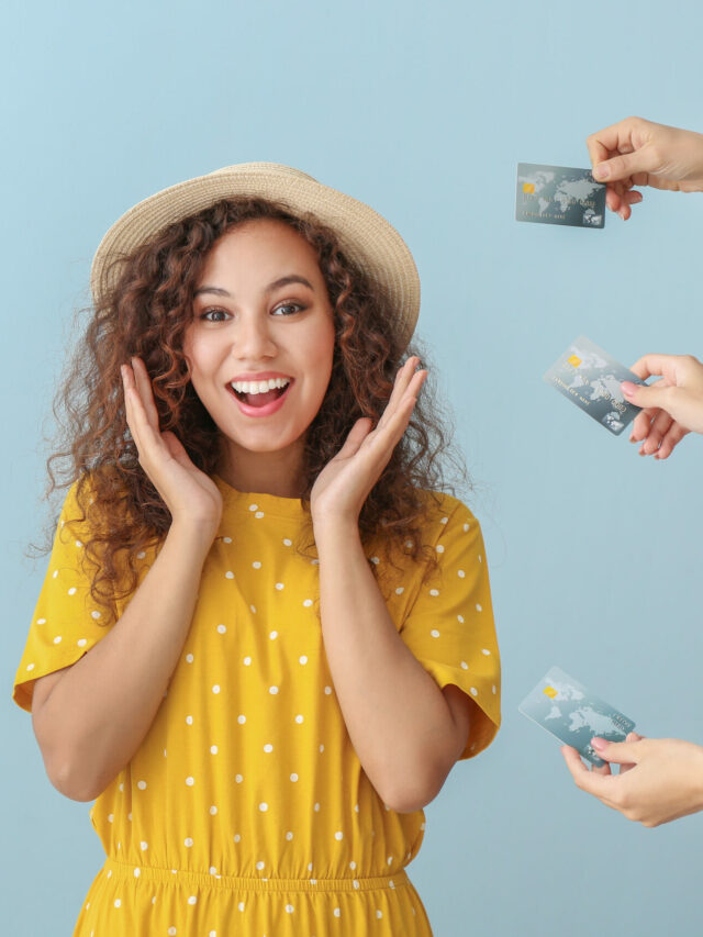 Young African-American woman and hands with credit cards on colo