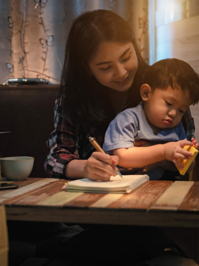 Single mom works at home and kid play near the mother in bedroom