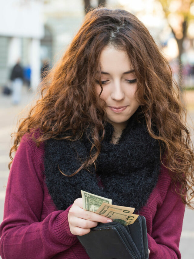 young shopper woman taking out money from wallet on street