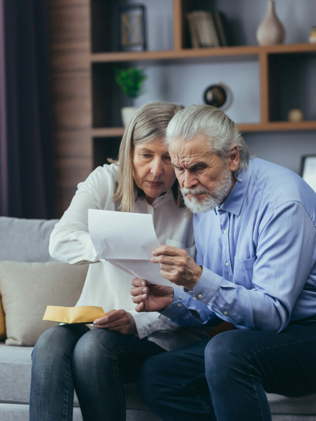 Angry frustrated document senior couple. Unhappy old family getting stressed. Serious older husband showing banking paper document bills taxes to confused elderly wife in home. Worried looking utility
